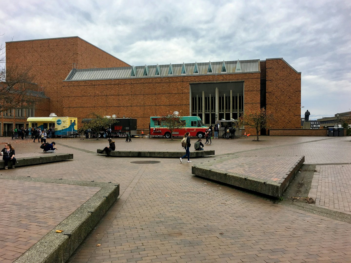 People gather at brightly colored food trucks in an outdoor plaza.