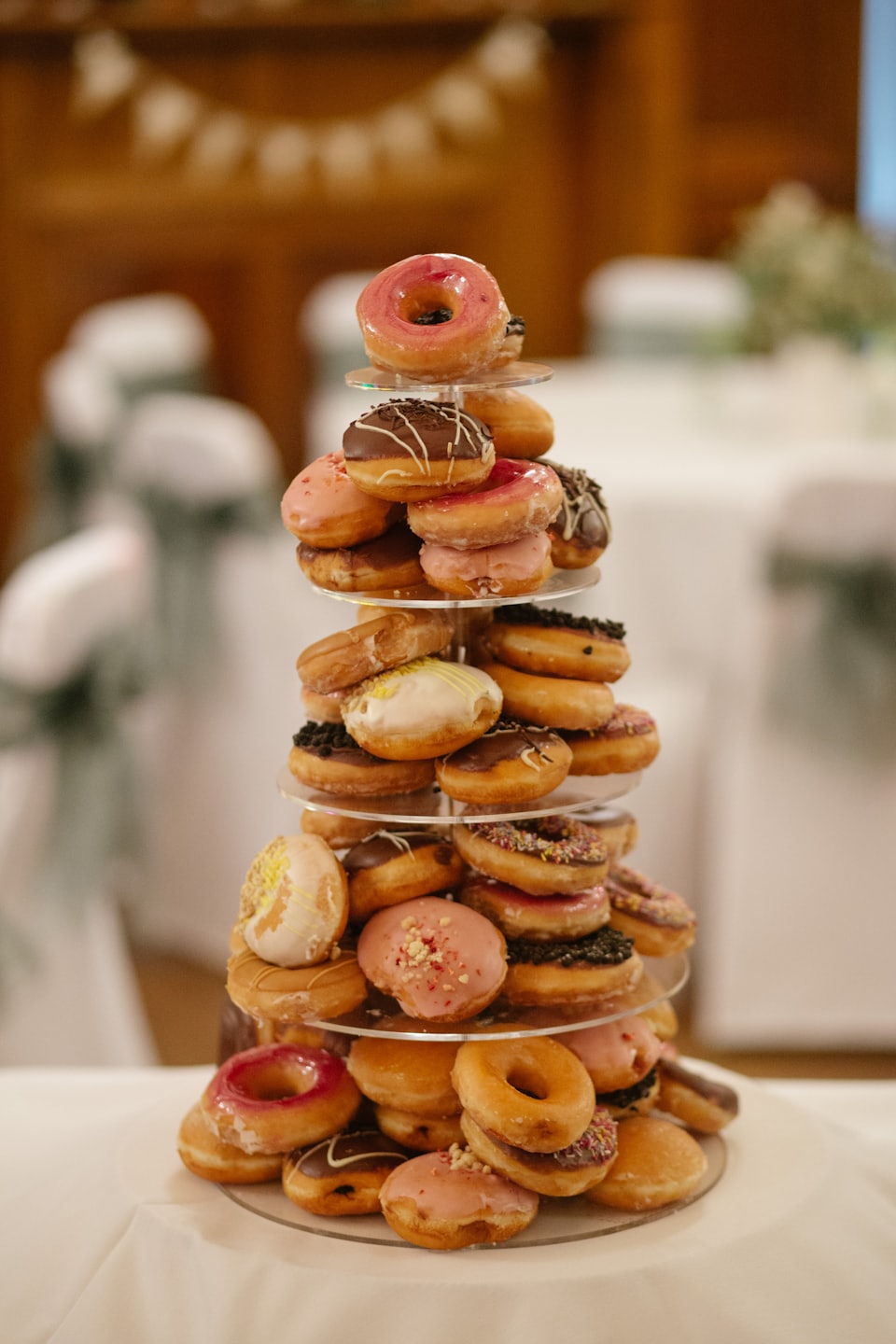 Tiered stand filled with various glazed and frosted donuts.