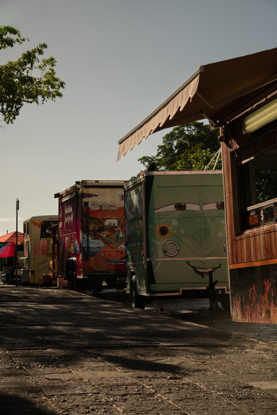 Colorful food trucks and stalls parked outdoors on a sunny day.