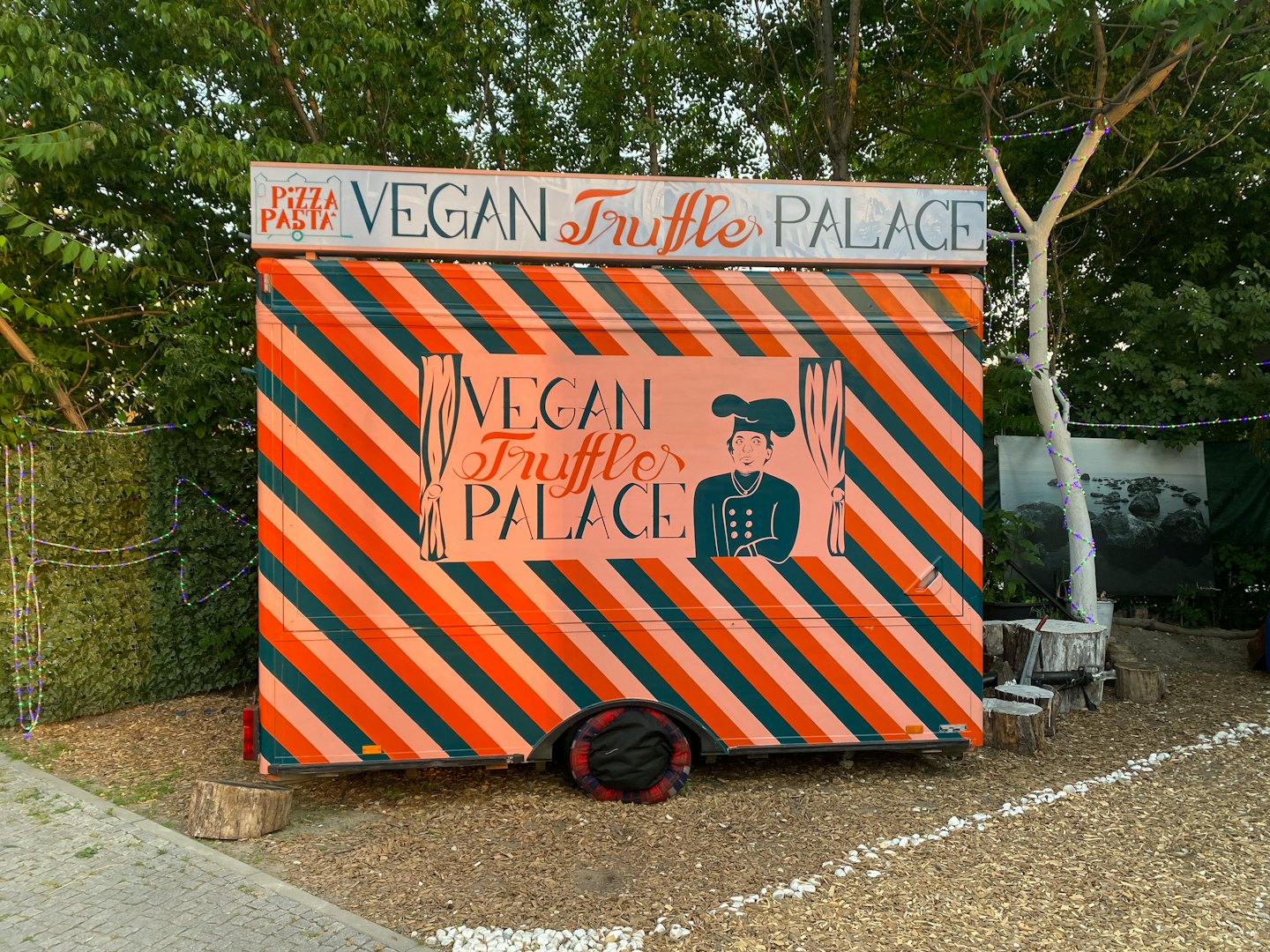 Vegan truffle pizza food truck with chef illustration on gravel.