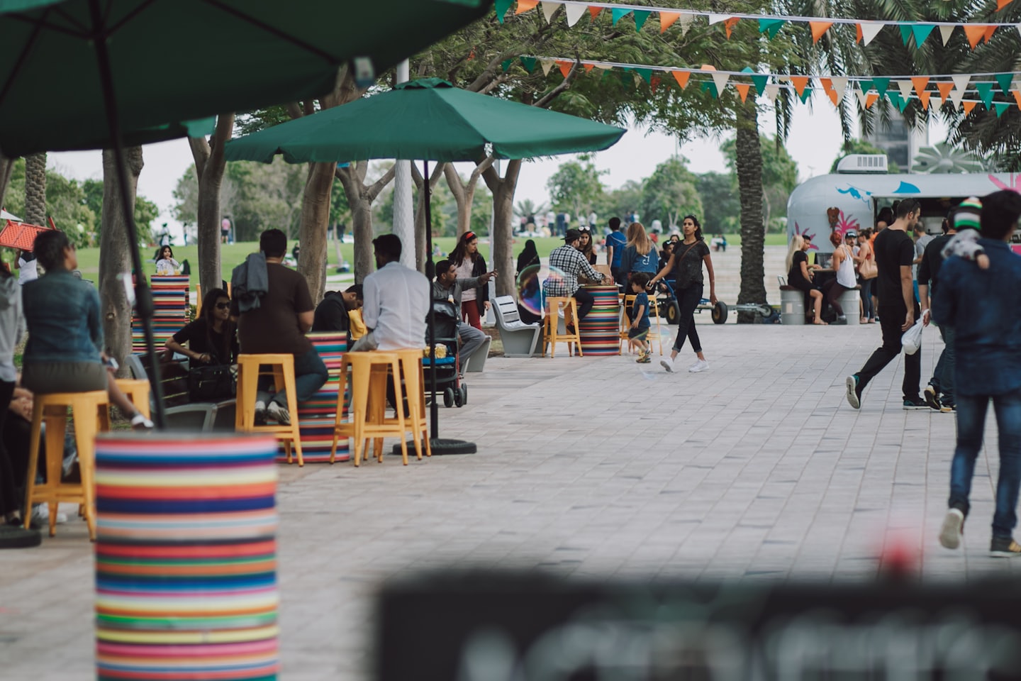 People dining and walking at a lively outdoor market with a food truck.
