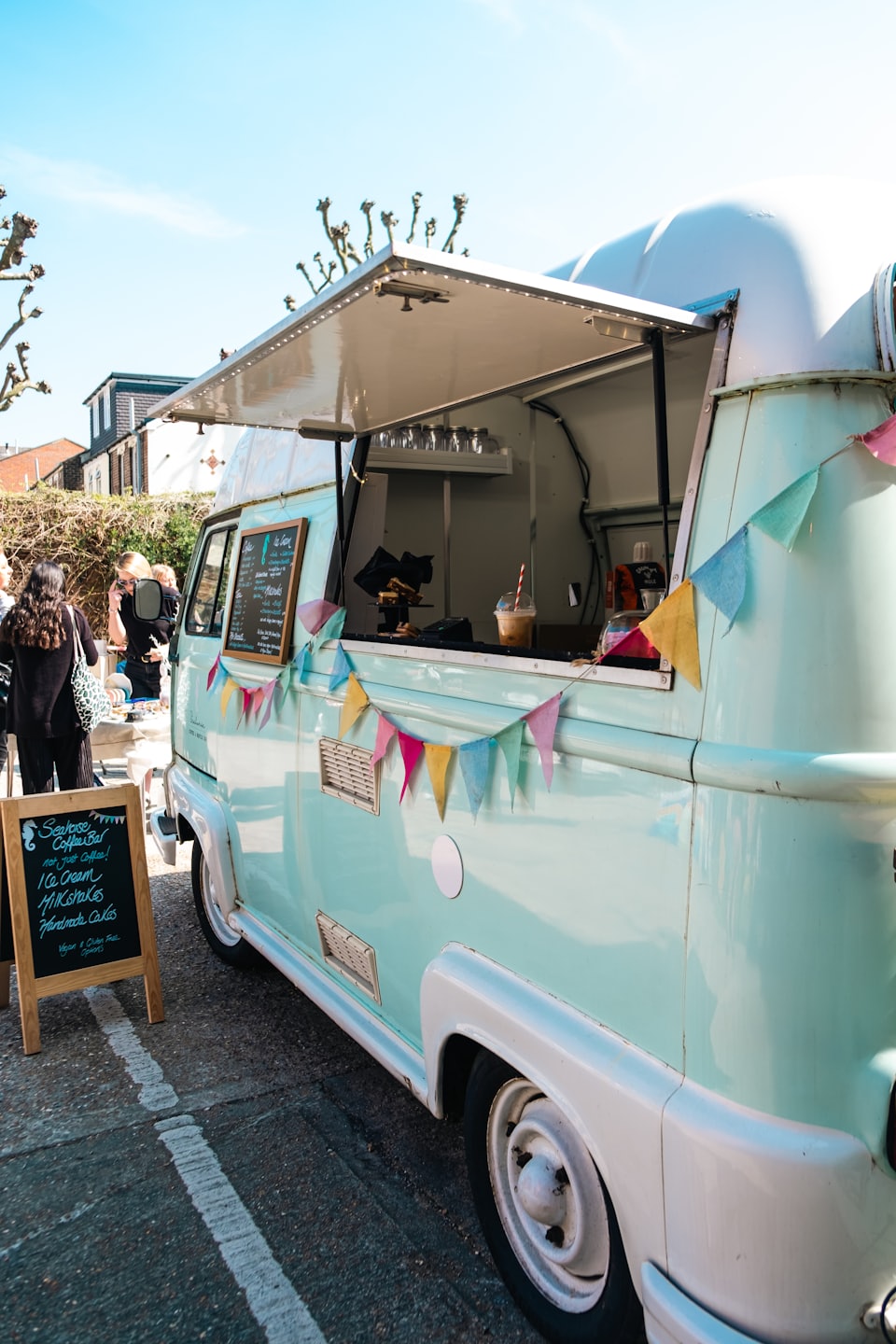 Mint green food truck with serving window open on a sunny day.