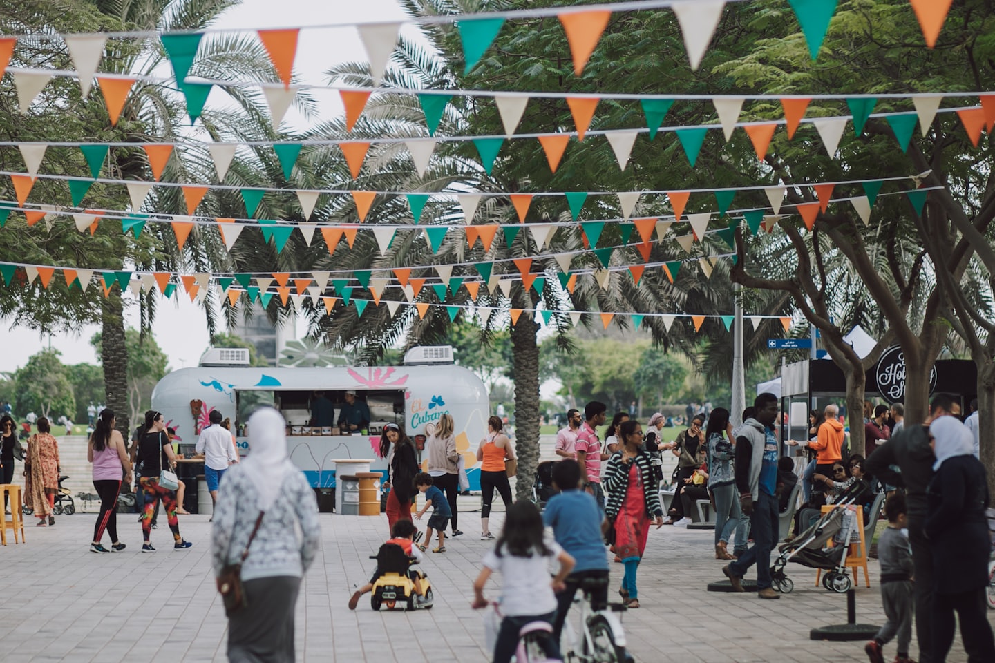 People at an outdoor festival with food trucks and bunting.