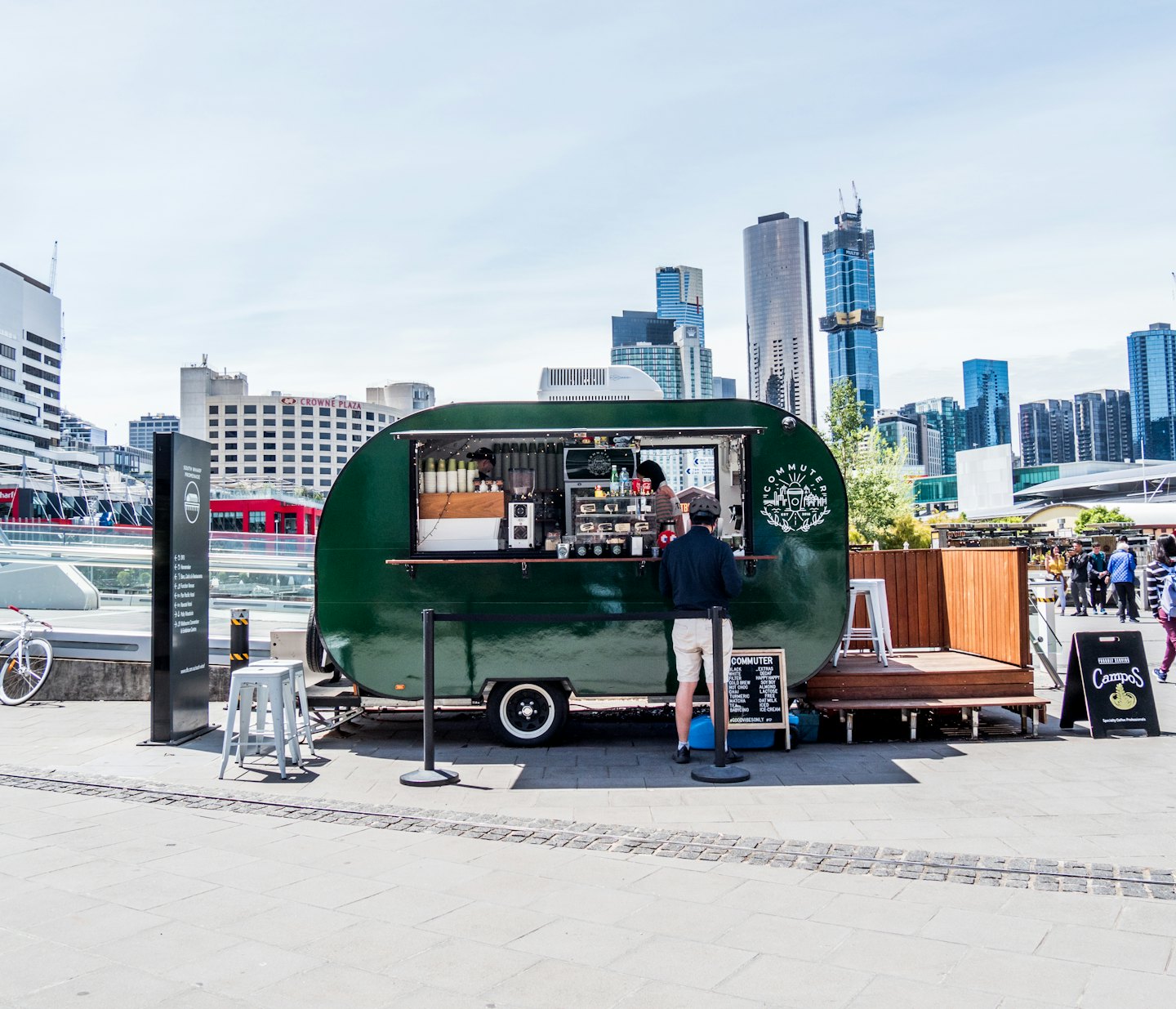 Customer ordering coffee at a green caravan food truck.