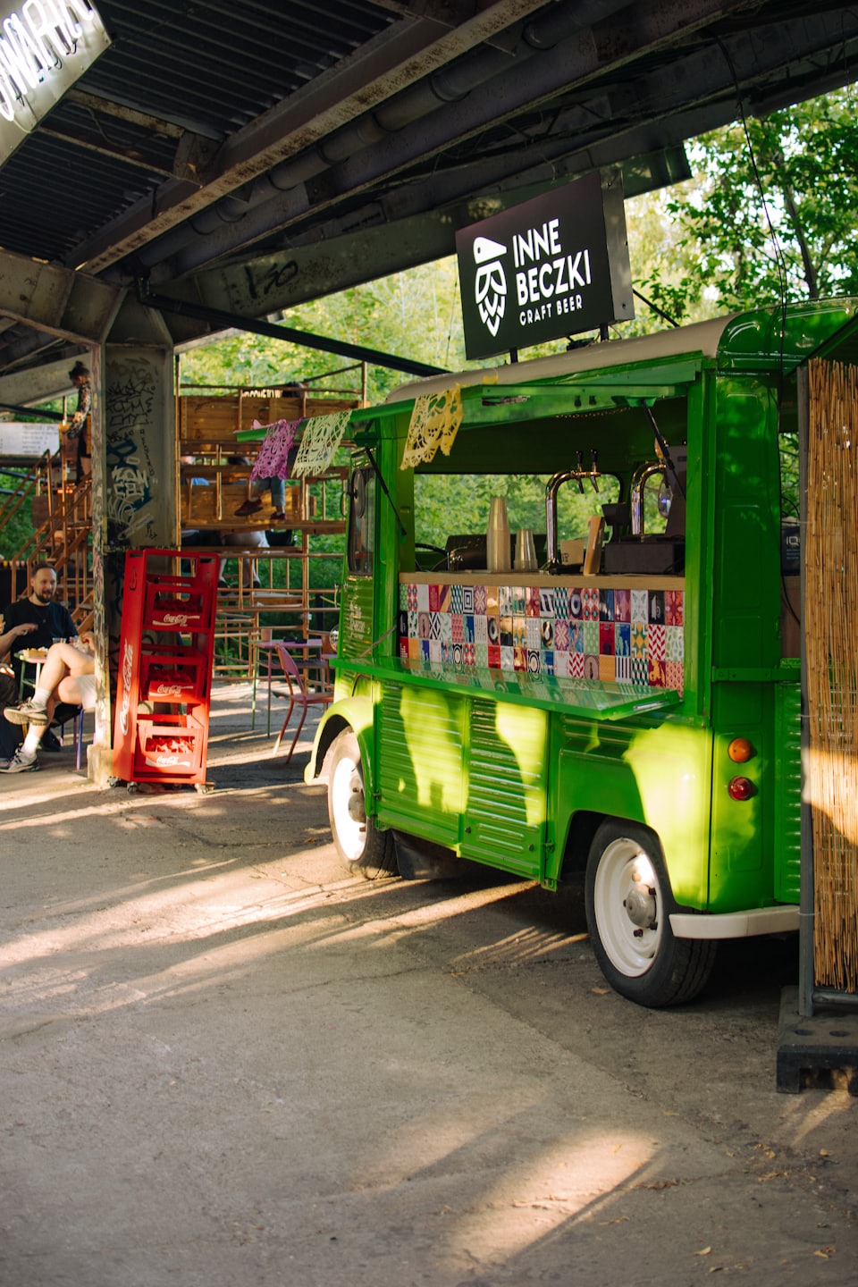 Green vintage food truck parked under a metal patio canopy.