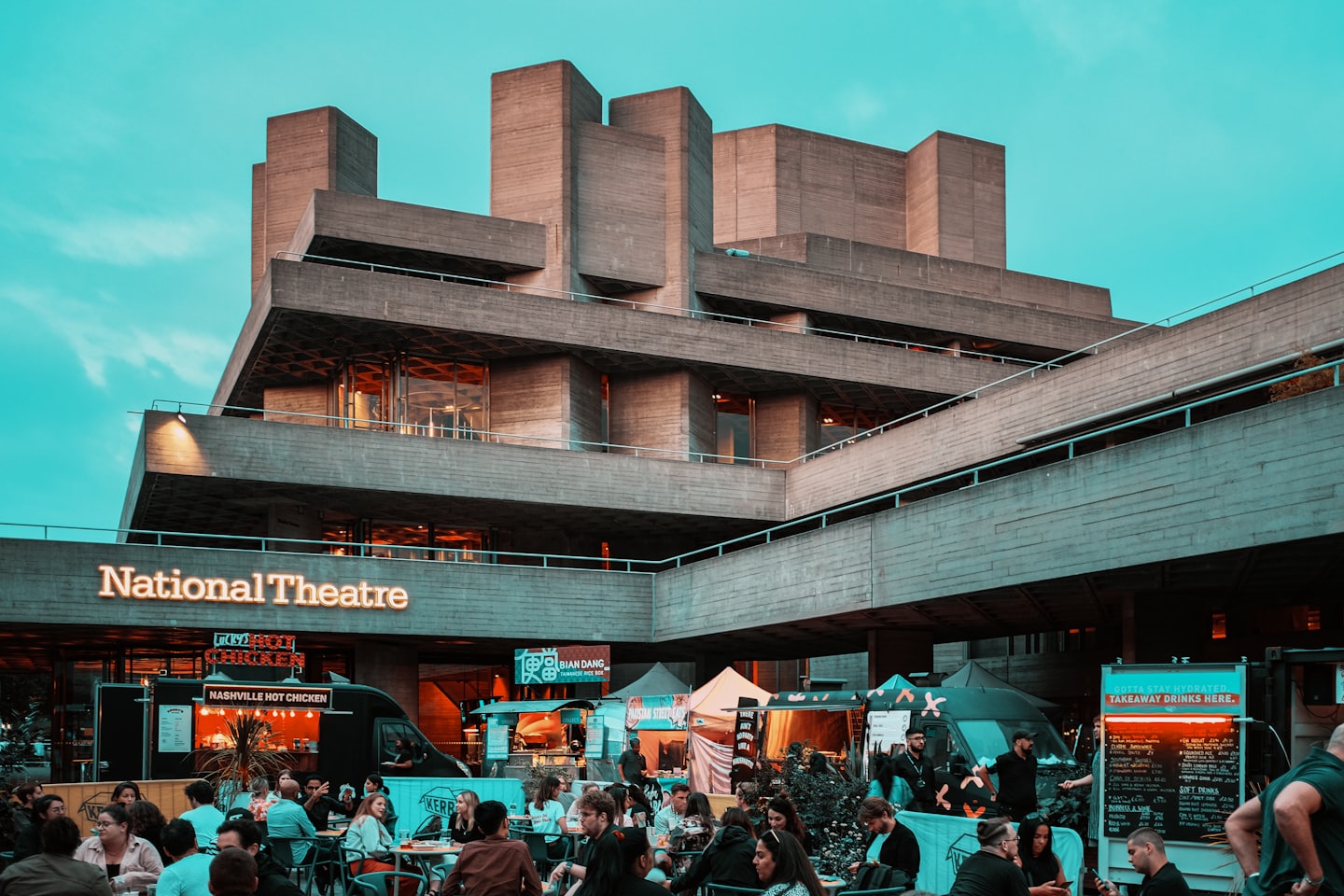 People dining at outdoor market stalls by the National Theatre.