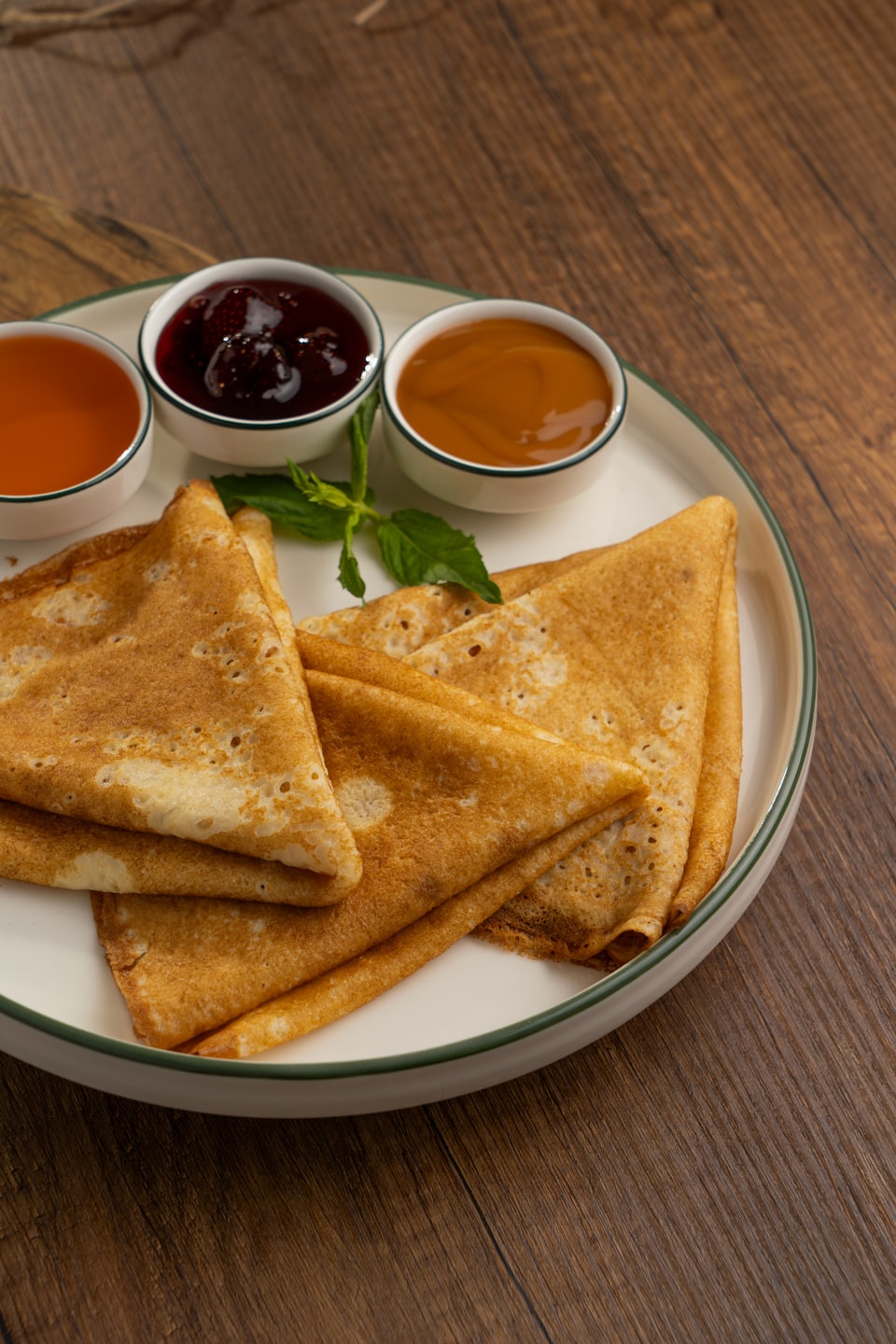 A stack of folded crepes served with bowls of sauces.
