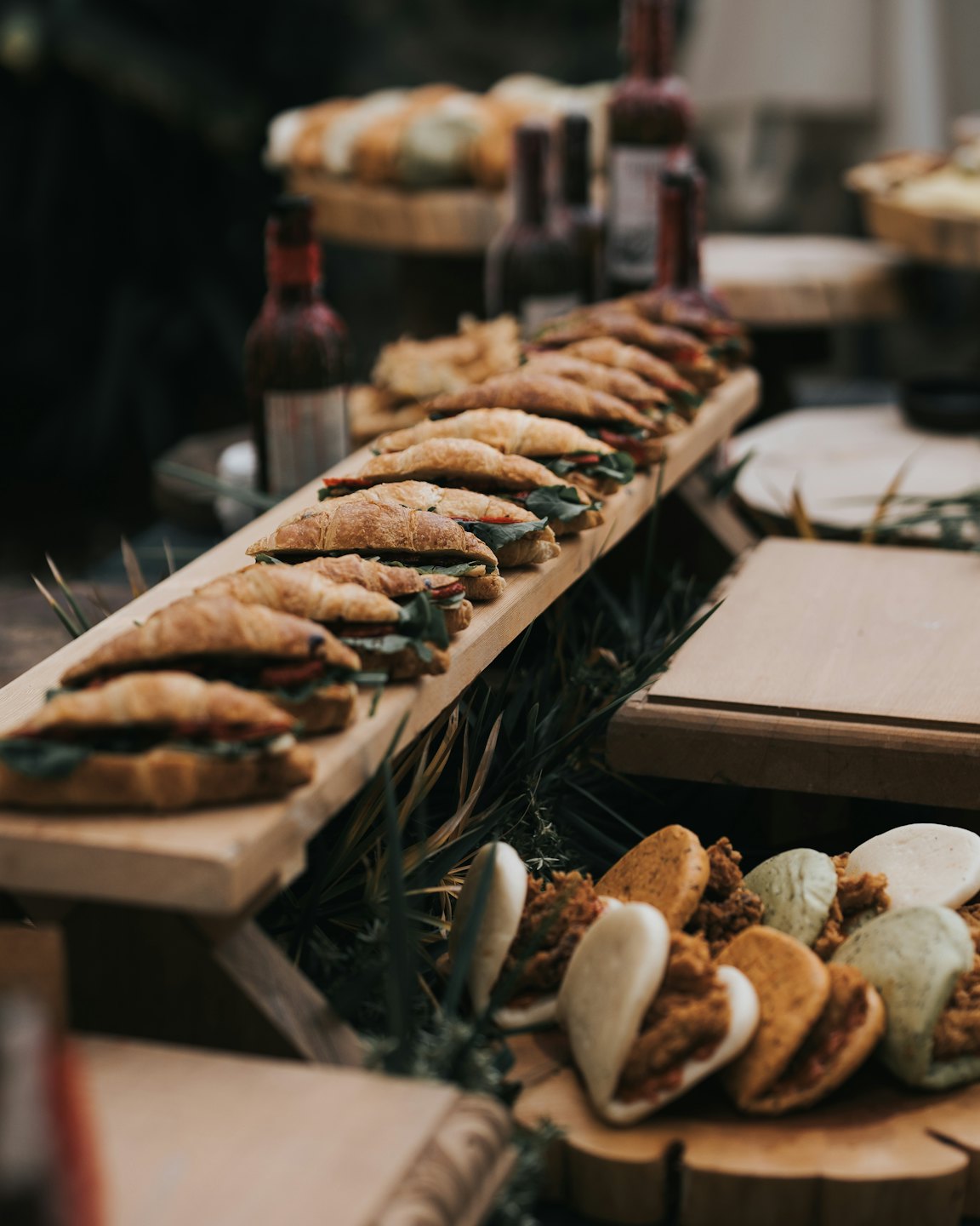 Miniature croissant sandwiches and bao buns on a wooden display.